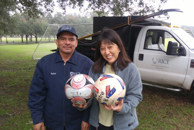 Rafael Rojas stands next to woman holding two soccer balls that he knocked down from a tree for her son.