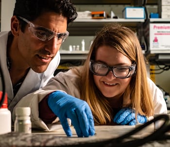 Rice University materials scientist Rafael Verduzco and graduate student Morgan Barnes check a sample while working on shape-shifting polymers. They have created a liquid crystal elastomer that can be molded into shapes that shift from one to another when heated. (Credit: Jeff Fitlow/Rice University)