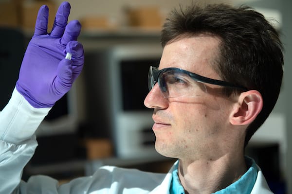 Rice University graduate student Sean Bittner holds a sample of a 3D-printed scaffold that may someday help heal osteochondral injuries of the kind often suffered by athletes. The material mimics the gradient structure of cartilage to bone found at the end of long bones. (Credit: Jeff Fitlow/Rice University)
