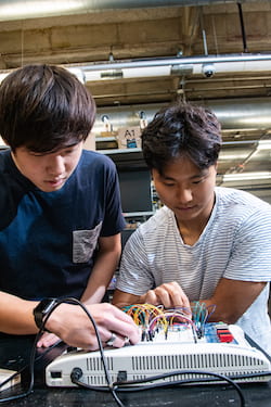 Takanori Iida, left, and Byung-UK Kang, senior engineering students at Rice University, work on the electronics test bed used to design a device that helps doctors secure rods that keep fractured bones in alignment. A sensor attached to a movable track finds the right spot to drill by pinpointing holes in the rod marked with magnets. (Credit: Jeff Fitlow/Rice University)