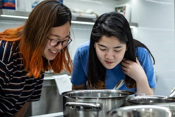 Rice University freshmen Minjung Kim, left, and So Jeong (Brianna) Lee cook a batch of coconut "mylk" in Rice's research kitchen. A class of students worked with an alumnus to refine a recipe for the vegan product. (Credit: Jeff Fitlow/Rice University)
