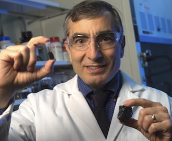 Rice University chemist James Tour holds coal and a vial of coal-derived graphene quantum dots. The dots have been modified for use as an effective antioxidant. (Credit: Jeff Fitlow/Rice University)