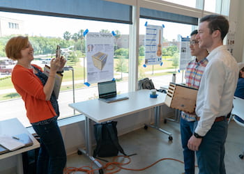 Rice University Professor Marcia O'Malley captures Andrew Low, center, and Eric Voigt with their digital theramin at an exhibition of mechatronic art at Rice's Moody Center for the Arts. (Credit: Brandon Martin/Rice University)
