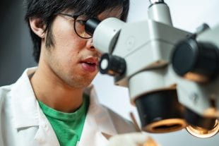 Rice graduate student Tong Chen looking into a microscope