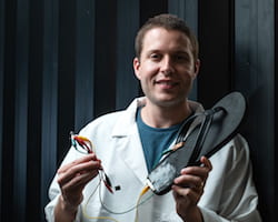 Rice University postdoctoral researcher Michael Stanford holds a flip-flop with a triboelectric nanogenerator, based on laser-induced graphene, attached to the heel. Walking with the flip-flop generates electricity with repeated contact between the generator and the wearer's skin. Stanford wired the device to store energy on a capacitor. (Credit: Jeff Fitlow/Rice University)