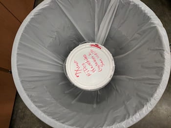 A plastic bucket and a plastic bag contain a 5-gallon supply of carbon nanotubes in a lab at Rice University, representing the beginning of the process to safely transfer the nanotubes for experimental use. The Rice lab published its technique in SN Applied Sciences. (Credit: Barron Research Group/Rice University)