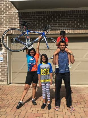 Sudha Yellapantula, left, raises her bike in triumph alongside her family after finishing 600 miles in a month.