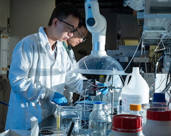 Rice University postdoctoral researcher Chuan Xia, left, and chemical and biomolecular engineer Haotian Wang adjust their electrocatalysis reactor to produce liquid formic acid from carbon dioxide. (Credit: Jeff Fitlow/Rice University)