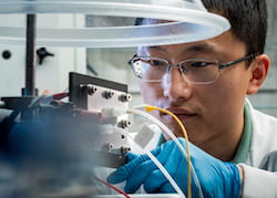 Rice University engineer Haotian Wang adjusts the electrocatalysis reactor built in his lab to recycle carbon dioxide to produce liquid fuel. The reactor is designed to be an efficient and profitable way to reuse the greenhouse gas and keep it out of the atmosphere. (Credit: Jeff Fitlow/Rice University)
