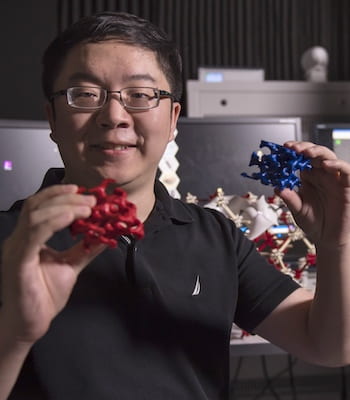 Rice University postdoctoral researcher Xueyan Feng holds "left" and "right" chiral models of the block copolymer double gyroid created in the lab of materials scientist Ned Thomas. The double gyroid lattice turned out to be less than perfect, as demonstrated by slicing away nanoscale layers of the polymer and imaging it with an electron microscope. (Credit: Tommy LaVergne/Rice University) 