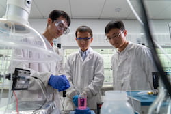 From left, Rice University researchers Yang Xia, Chuan Xia and Haotian Wang demonstrate how hydrogen peroxide freshly produced by their reactor purifies a contaminant in water. The reactor uses just air, water and electricity to produce the valuable chemical. (Credit: Brandon Martin/Rice University)