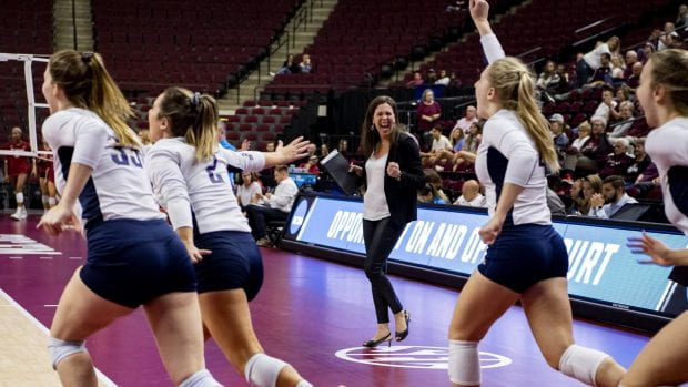 Head coach Genny Volpe (middle) and the Rice volleyball team celebrates its victory over Oklahoma Dec. 5 in College Station, Texas. (Photo by Maria Lysaker/Rice Athletics)