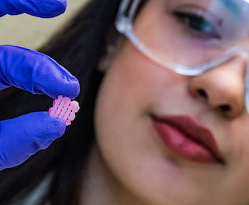 Rice University research scientist Maryam Elizondo holds a 3D-printed scaffold engraved with grooves for the deposition of live cells for implantation. The scaffold facilitates the growth of new tissues as it degrades. By protecting cells in grooves along the printed lines, Rice researchers designed the scaffold to enable different tissue-type layers within one scaffold. (Credit: Jeff Fitlow/Rice University)