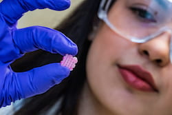 Rice University research scientist Maryam Elizondo holds a 3D-printed scaffold engraved with grooves for the deposition of live cells for implantation. The scaffold facilitates the growth of new tissues as it degrades. By protecting cells in grooves along the printed lines, Rice researchers designed the scaffold to enable different tissue-type layers within one scaffold. (Credit: Jeff Fitlow/Rice University)