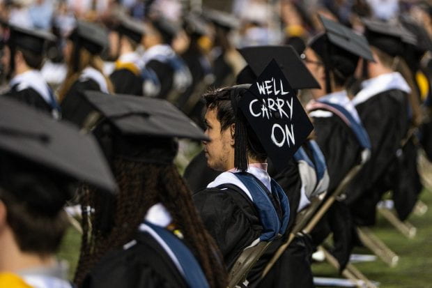 A Rice Class of 2021 senior wears a mortarboard that says "We'll carry on."