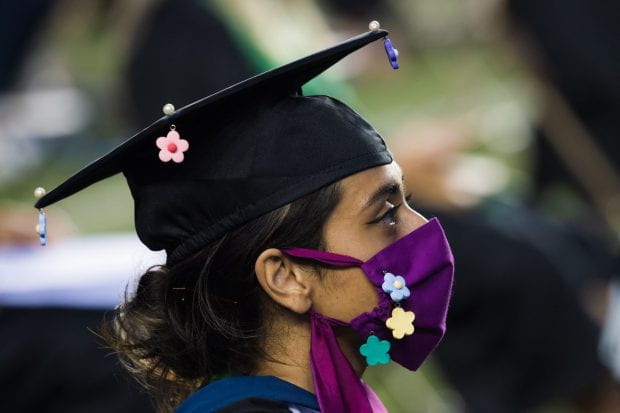 A Rice student wears a matching face mask and mortarboard.