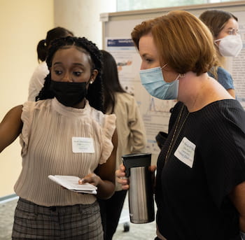 CAPTION: Ruth Adaimoabasi Udo, left, discusses her work with Marcia O’Malley, Rice’s Thomas Michael Panos Family Professor in Mechanical Engineering, Electrical and Computer Engineering, and Computer Science, at the IBB Summer Undergraduate Research Symposium. Udo won the Outstanding Poster Award for the EngMed REU program. Photo by Jeff Fitlow